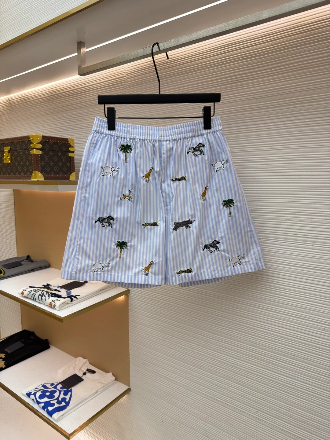 LOUIS VUITTON Animal and plant nostalgic style embroidered striped shorts ●Original version: purchased and developed by 14616 ●Item number: 1682542-A75 ●Fabric: cotton fabric ●Technology: embroidery production ●Color: blue ●Version: fitted version ●Weight: about 205 grams ●Size: S-M-L-XL ●Description: Made of high-count pure cotton poplin fabric. After pre-washing process, it feels smooth and breathable. It has both drape and stiffness, and is not easy to wrinkle and deform. The blue and white vertical stripes on the body are woven with yarn-dyed technology, and the texture is clear and does not fade. The animal and coconut tree patterns are presented with sophisticated embroidery technology. The embroidery threads are full of color and the stitches are dense. The patterns are three-dimensional and vivid, forming a rich visual hierarchy with the stripe base. The shirt has a Cuban collar style, with smooth necklines, custom mother-of-pearl buttons at the placket, and a warm texture. The overall shape is loose, the shoulder joints are straight and fine, the cuffs are cuffed with exquisite craftsmanship, custom accessories and three logos are complete, and the details are full of luxury craftsmanship. It is suitable for casual vacations and daily outings, etc. The overall wiring is straight and delicate, the fabric is comfortable and soft, and the color is consistent without color difference. It can be matched with the same style to create a fashionable look and control various occasions. Customized accessories, complete with three standards, same style for men and women!